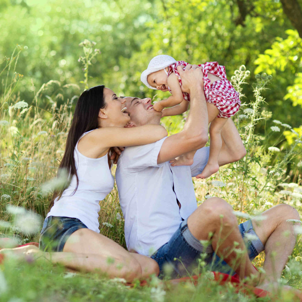 Happy young family spending time together in green nature.